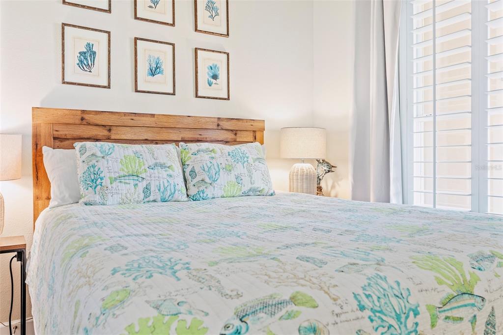 A bedroom features a wooden headboard, coastal-themed bedding, and framed artwork on the wall — 15 OCEAN CREST WAY UNIT 1312, PALM COAST, FL