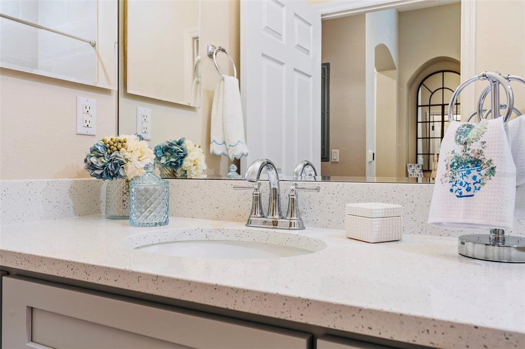 A bathroom vanity features a white speckled countertop, a chrome faucet, and a large mirror — 15 OCEAN CREST WAY UNIT 1312, PALM COAST, FL