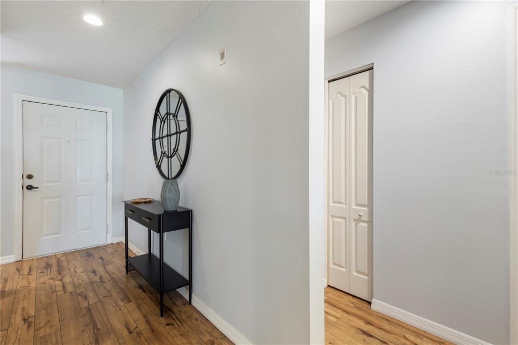 An entryway features light blue walls, wood-look flooring, a black console table, and a closet — 8750 OLDE HICKORY AVENUE UNIT 9103, SARASOTA, FL