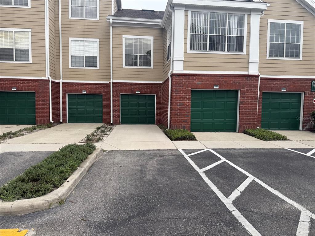 A row of townhome garages with green doors and concrete driveways in front — 13028 PLANTATION PARK CIRCLE UNIT 1225, ORLANDO, FL