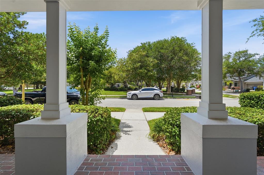 A view from a covered porch looking out toward a street with parked cars — 10111 HAYFIELD WAY, TAMPA, FL