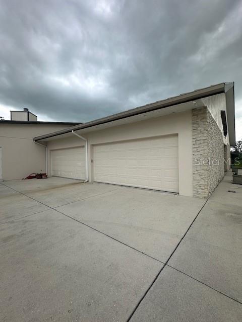 A side view of a house exterior featuring two garage doors and stone veneer siding — 15986 CUTTING HORSE TRAIL, MYAKKA CITY, FL