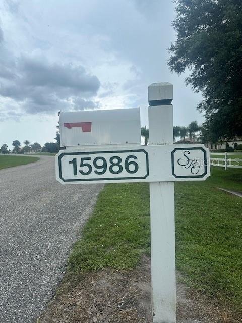 A white mailbox post displays the house number 15986 and a decorative monogram sign — 15986 CUTTING HORSE TRAIL, MYAKKA CITY, FL