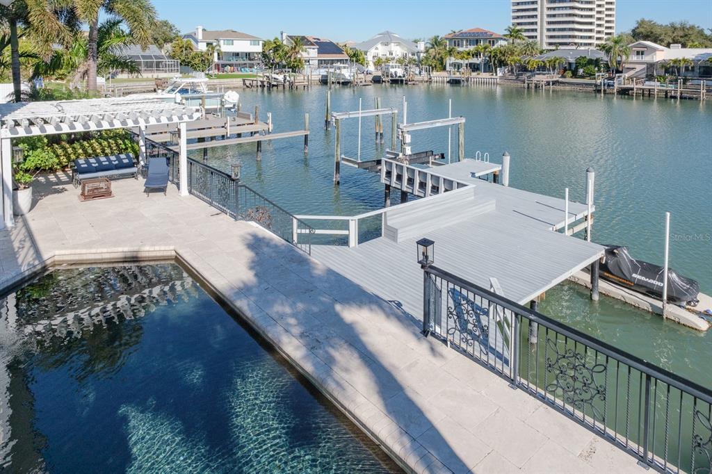 A swimming pool sits next to a wooden dock and boat lift on a canal — 5949 SEABIRD DRIVE S, GULFPORT, FL