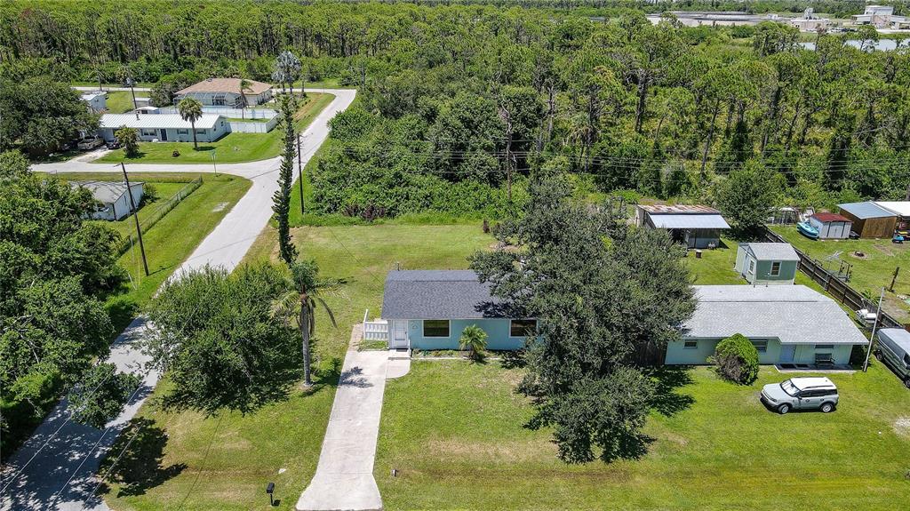 An aerial view shows a light blue house with a driveway and surrounding grassy yard — 8382 OSPREY ROAD, ENGLEWOOD, FL