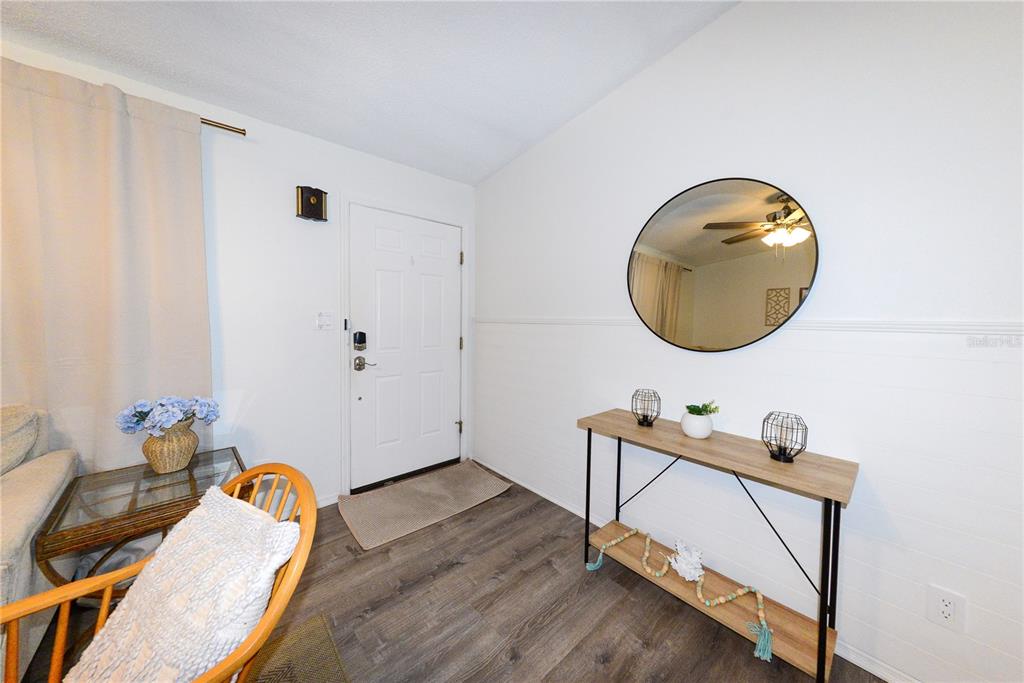 An entryway features a white door, a wood-topped console table, and a round wall mirror — 8382 OSPREY ROAD, ENGLEWOOD, FL