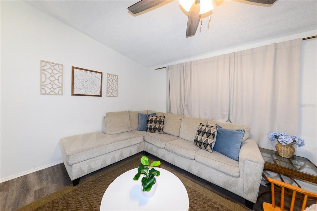 A living room features a beige sectional sofa, a white coffee table, and wall art — 8382 OSPREY ROAD, ENGLEWOOD, FL