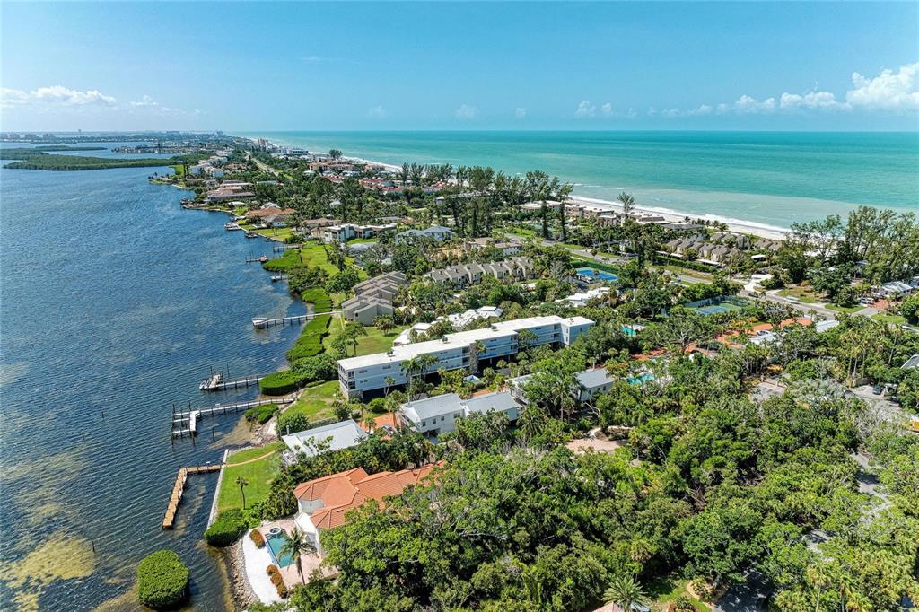 An aerial view of a coastal property featuring waterfront homes, apartment buildings, and sandy beaches — 5320 GULF OF MEXICO DRIVE UNIT 204, LONGBOAT KEY, FL