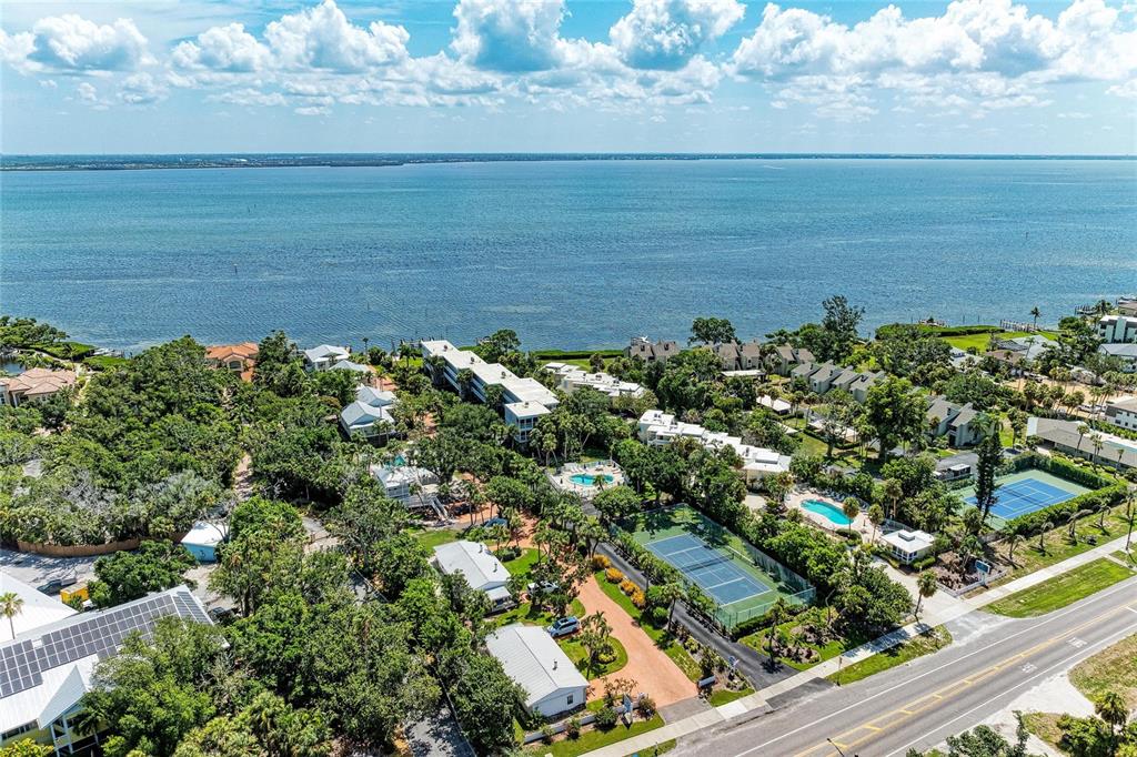 An aerial view shows a coastal residential complex with tennis courts, pools, and lush landscaping — 5320 GULF OF MEXICO DRIVE UNIT 204, LONGBOAT KEY, FL
