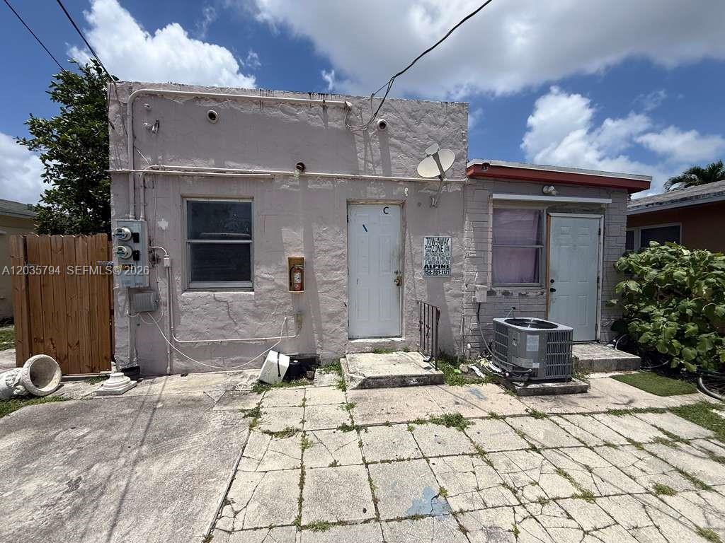 The exterior of a single-story, light-colored concrete building features two doors and a window — 2014 Funston St # C, Hollywood FL 33020, HOLLYWOOD, FL