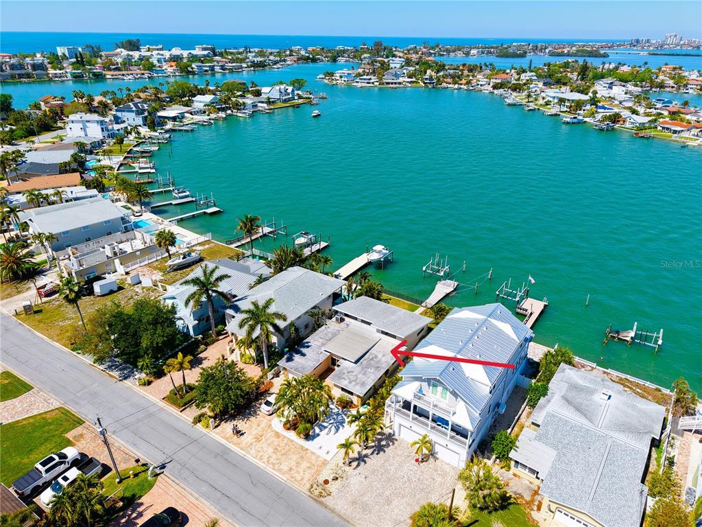 An aerial view shows a waterfront house with a red arrow pointing to its roof — 468 20TH AVENUE, INDIAN ROCKS BEACH, FL