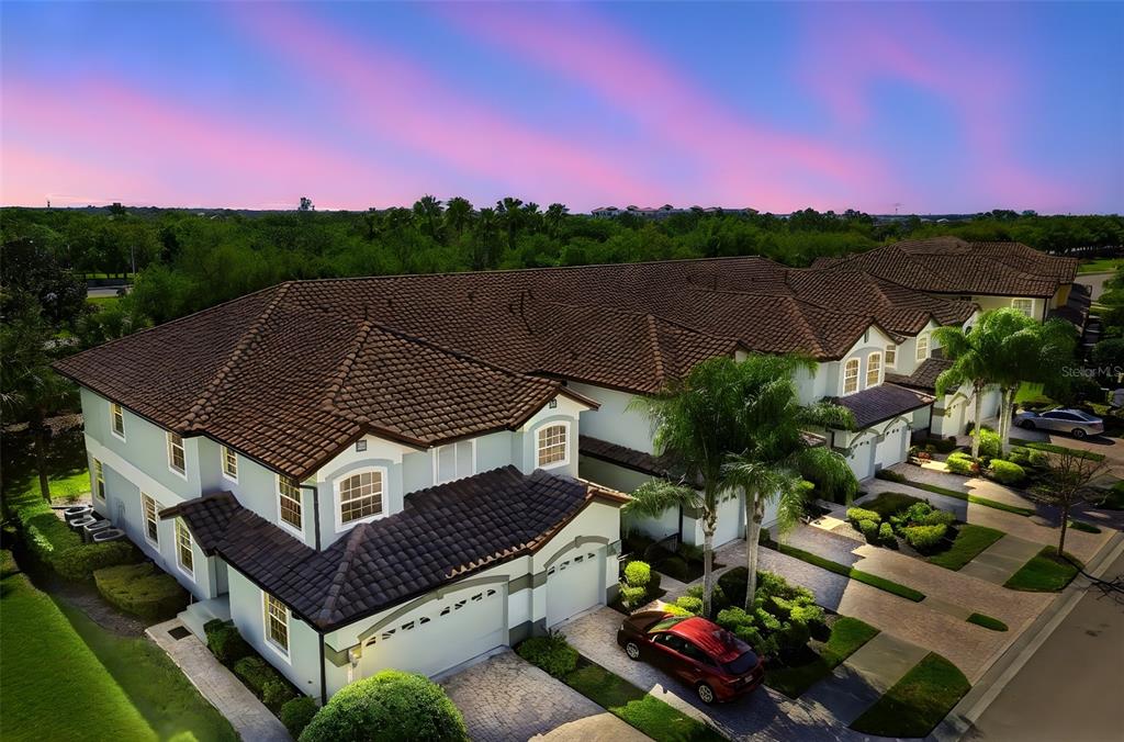 An aerial view shows a multi-unit townhouse complex with brown tile roofs at sunset — 8235 MIRAMAR WAY, LAKEWOOD RANCH, FL