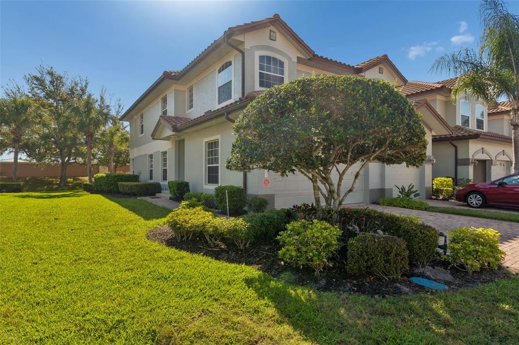 A two-story suburban house with a tan stucco exterior, tile roof, and a landscaped front yard — 8235 MIRAMAR WAY, LAKEWOOD RANCH, FL