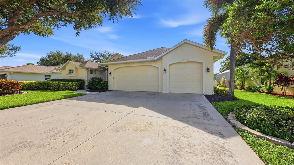 A single-story house with a two-car garage and a concrete driveway under a blue sky — 6228 AVENTURA DRIVE, SARASOTA, FL
