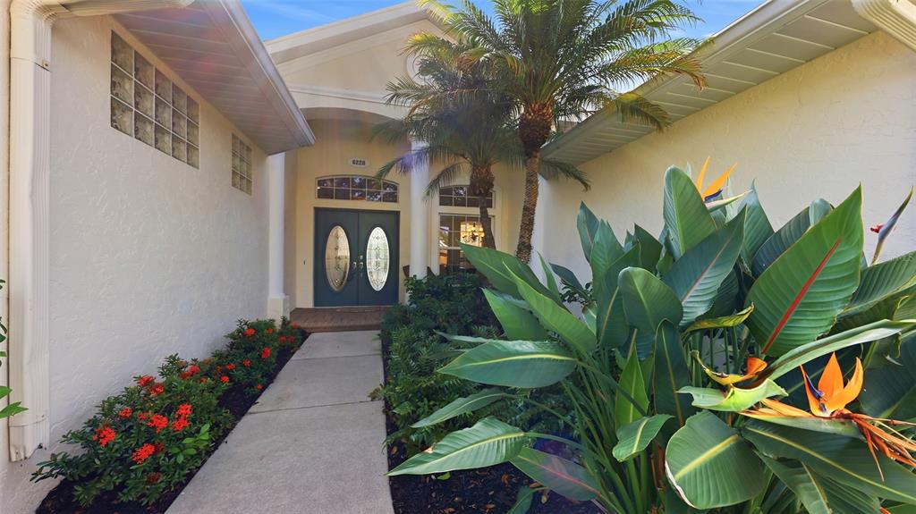 A concrete walkway leads to a double front door with glass inserts and palm landscaping — 6228 AVENTURA DRIVE, SARASOTA, FL