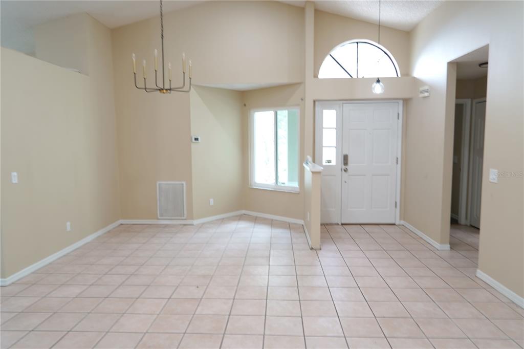 An entryway and dining area with vaulted ceilings, tile flooring, and a white front door — 4304 BARRET AVENUE, PLANT CITY, FL