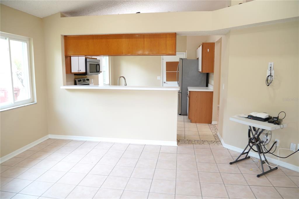 A kitchen with wood cabinets and a breakfast bar overlooks a tiled dining area — 4304 BARRET AVENUE, PLANT CITY, FL
