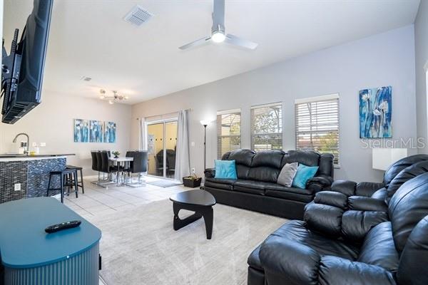 A living room with a black leather sofa, a dining area, and a kitchen counter — 3163 YELLOW LANTANA LANE, KISSIMMEE, FL