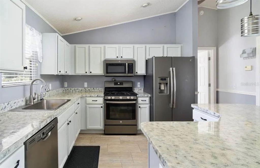 A kitchen with white cabinets, granite countertops, and stainless steel appliances — 104 CHERRY BLOSSOM LANE, LADY LAKE, FL