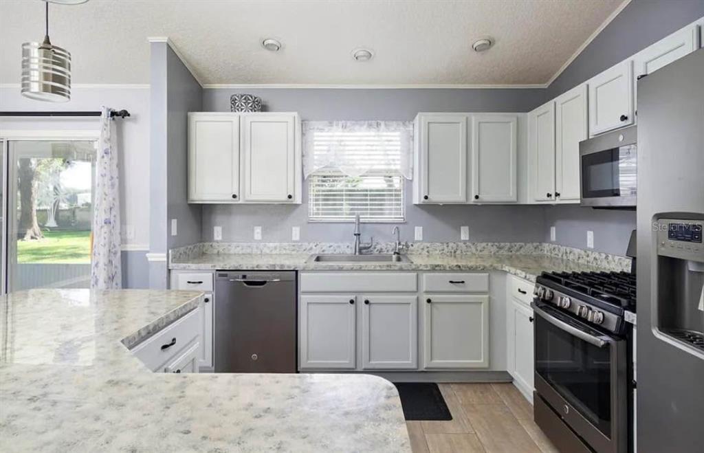 A kitchen with white cabinets, stainless steel appliances, and light-colored granite countertops — 104 CHERRY BLOSSOM LANE, LADY LAKE, FL