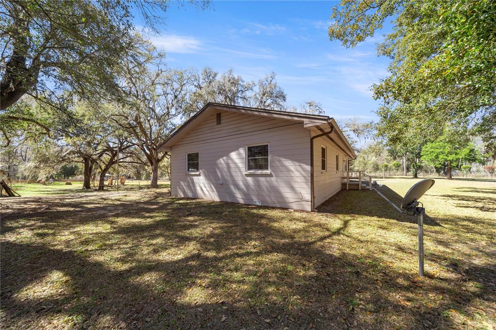 A side view of a single-story house with light-colored siding and a satellite dish — 3910 SE 52ND STREET, OCALA, FL