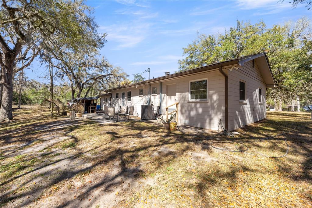 The exterior of a single-story house with light-colored siding and a concrete patio area — 3910 SE 52ND STREET, OCALA, FL