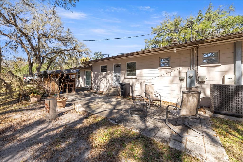 A concrete patio sits behind a single-story house with light siding and a metal shed — 3910 SE 52ND STREET, OCALA, FL