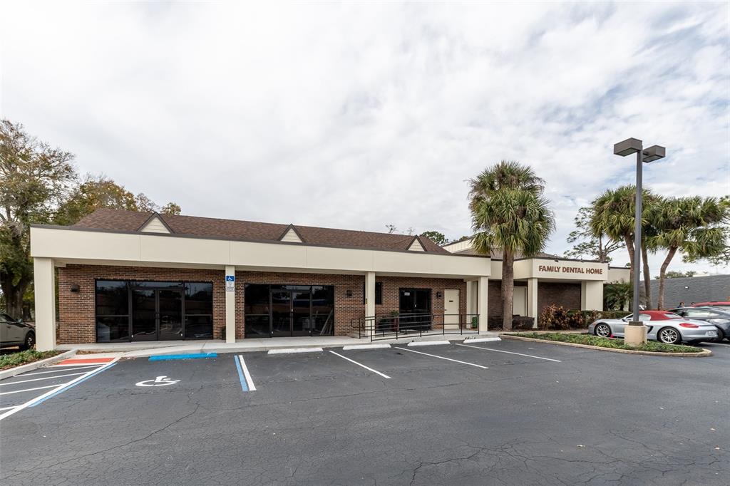 The exterior of a single-story brick commercial building features a parking lot and palm trees — 945 STATE ROAD 436 UNIT B and C, CASSELBERRY, FL