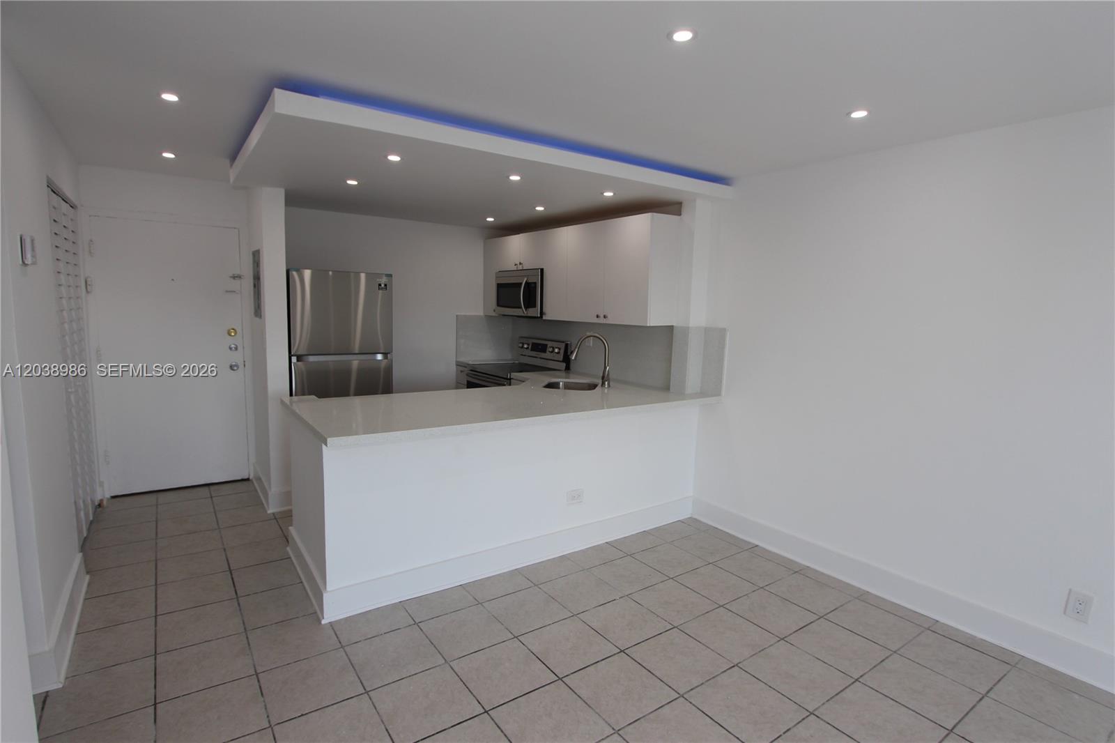 A kitchen with white cabinets, stainless steel appliances, and a breakfast bar on tiled floors — 801 NW 47th Ave # 614W, Miami FL 33126, MIAMI, FL