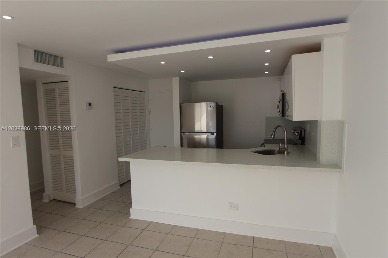 A kitchen features white cabinets, stainless steel appliances, and a peninsula counter with a sink — 801 NW 47th Ave # 614W, Miami FL 33126, MIAMI, FL