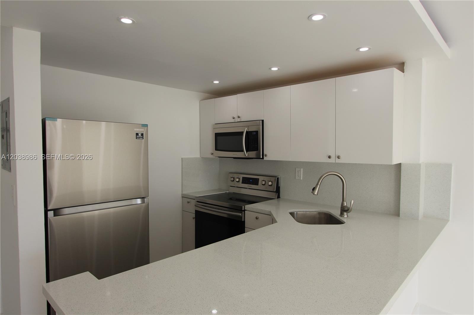 A modern kitchen features white cabinetry, stainless steel appliances, and light-colored quartz countertops — 801 NW 47th Ave # 614W, Miami FL 33126, MIAMI, FL