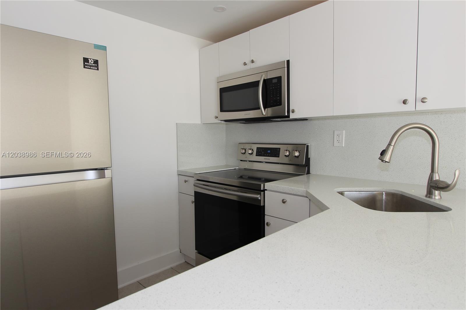 A kitchen features white cabinets, stainless steel appliances, and light-colored quartz countertops — 801 NW 47th Ave # 614W, Miami FL 33126, MIAMI, FL