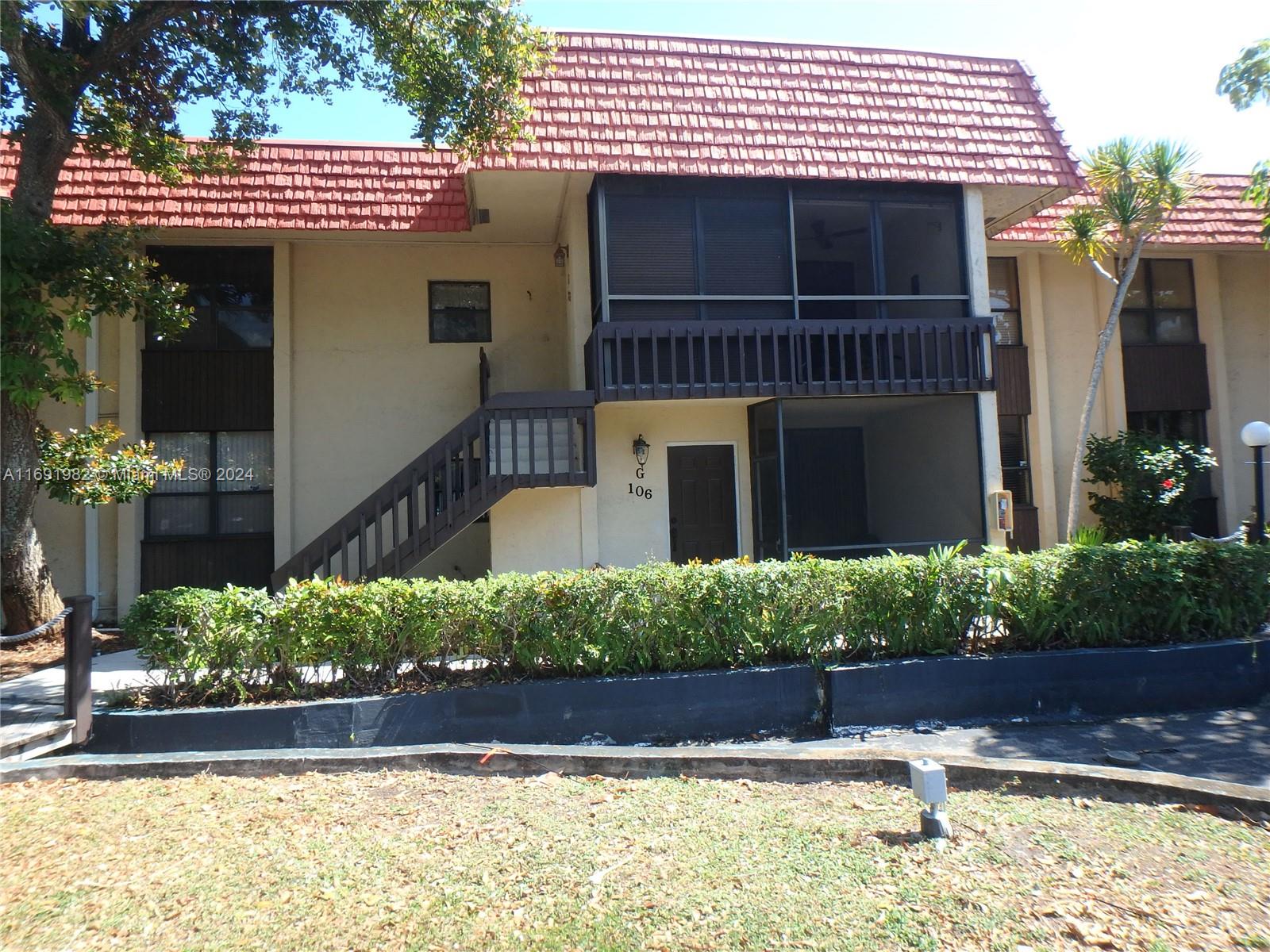 A two-story building features a brown staircase, a screened balcony, and a red tiled roof — 740 NE 199th St # 206G, Miami FL 33179, MIAMI, FL