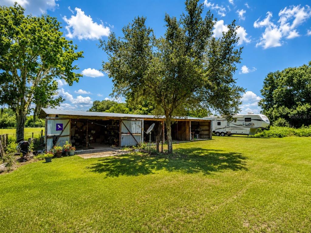 A one-story house with a covered front porch, screened-in side area, and light-colored siding — 13691 S HWY 25, EASTLAKE WEIR, FL