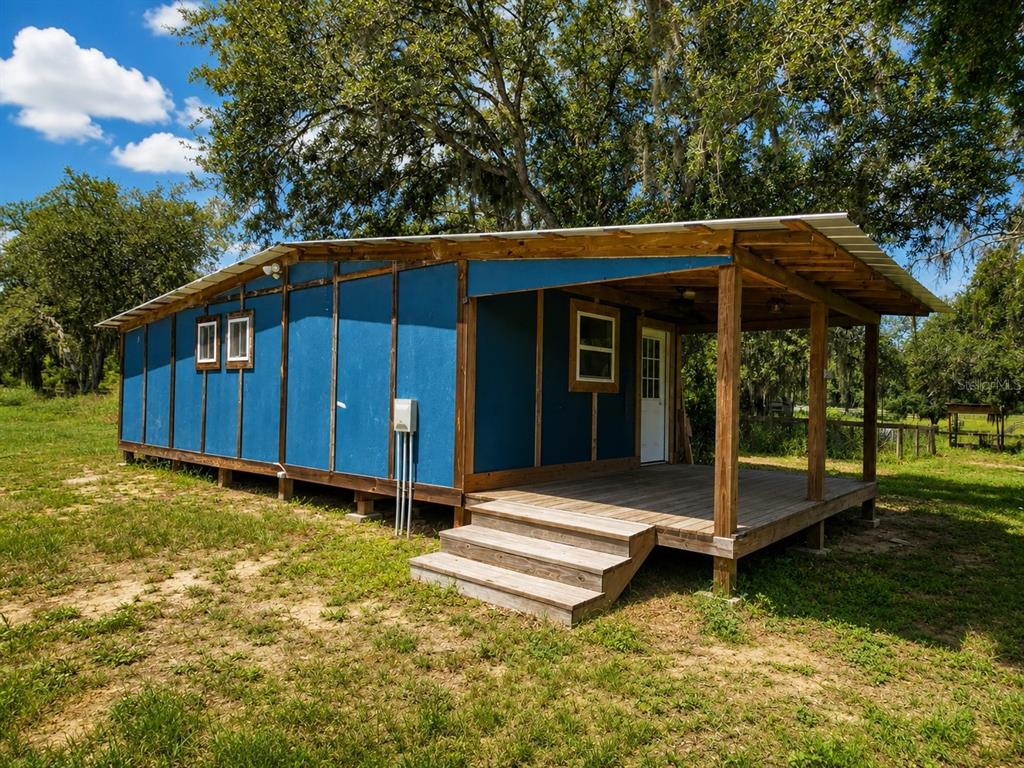 A screened-in porch with wood decking, white walls, and views of a grassy yard — 13691 S HWY 25, EASTLAKE WEIR, FL