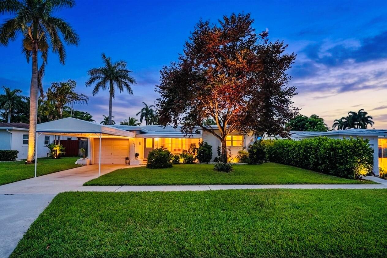 A single-story house with a carport and a large tree in the front yard at dusk — 707 N 32nd Avenue, Hollywood FL 33021, HOLLYWOOD, FL