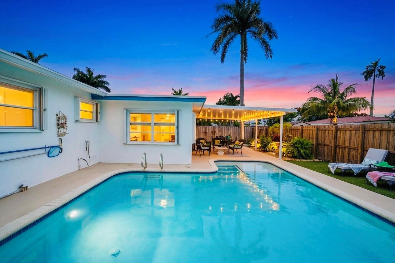 A backyard swimming pool with a covered patio and palm trees at sunset — 707 N 32nd Avenue, Hollywood FL 33021, HOLLYWOOD, FL