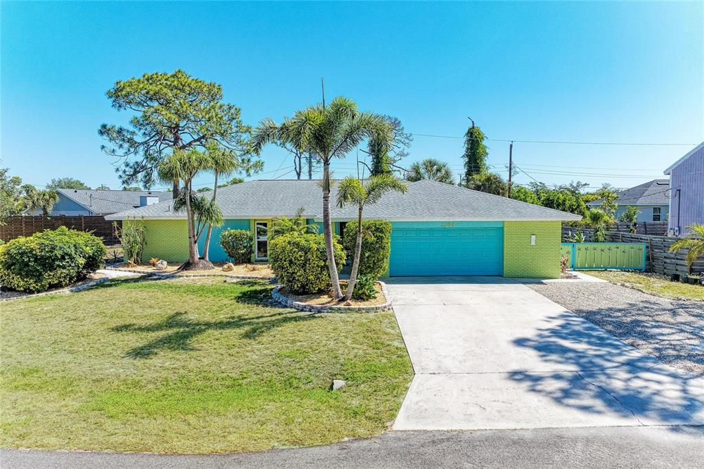 A single-story house with a lime green brick exterior, turquoise garage door, and palm trees — 1184 KENISCO ROAD, VENICE, FL