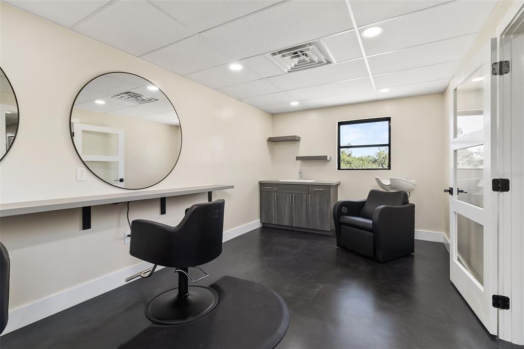 A salon room features a styling chair, a shampoo station, a mirror, and dark flooring — 1900 TAMIAMI TRAIL UNIT C & D, PUNTA GORDA, FL