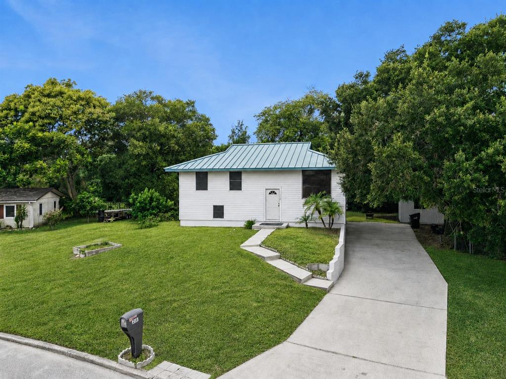 A white, single-story house with a metal roof sits behind a lawn and concrete driveway — 218 LAVENDER COURT, ORLANDO, FL