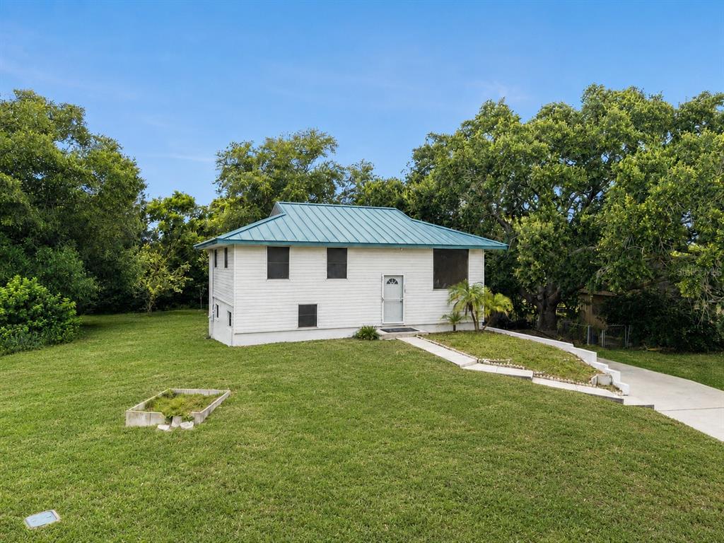 A white, single-story house with a blue metal roof sits on a grassy lawn — 218 LAVENDER COURT, ORLANDO, FL