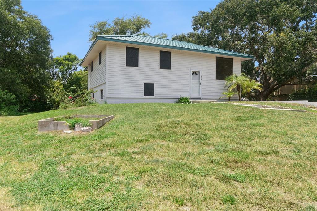 A white two-story house with a green metal roof sits on a grassy sloped lot — 218 LAVENDER COURT, ORLANDO, FL