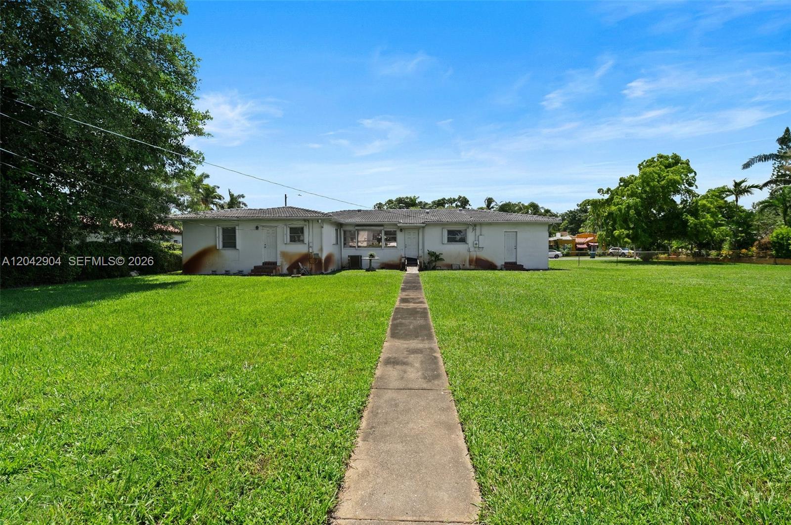 A single-story white house with a concrete walkway sits in a large grassy yard — 20 SW 4th St, Dania Beach FL 33004, DANIA BEACH, FL