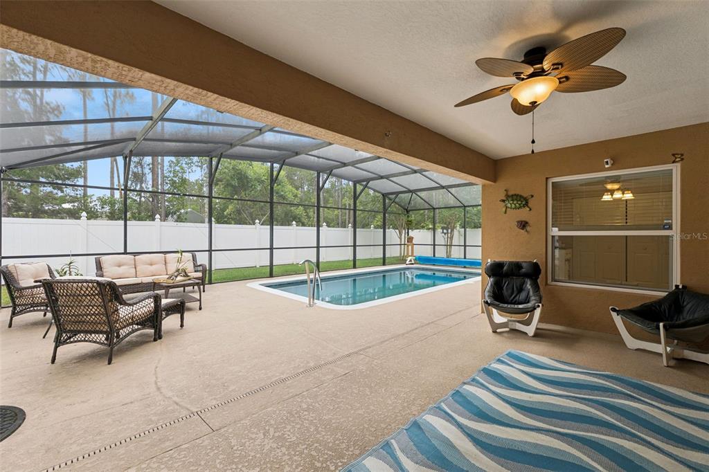 A covered patio features a swimming pool, wicker furniture, and a ceiling fan — 68 KATHLEEN TRAIL, PALM COAST, FL