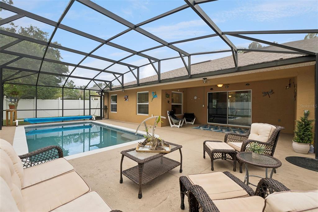 A screened-in patio features a swimming pool, outdoor furniture, and a tan stucco exterior — 68 KATHLEEN TRAIL, PALM COAST, FL
