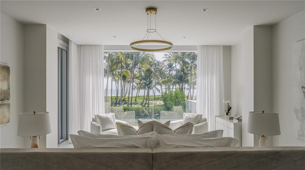 A bedroom with a large window overlooking a beach with palm trees and the ocean — Ocean Drive FOUR SEASONS PRIVATE RESIDENCES UNIT 6101, RIO GRANDE, PR