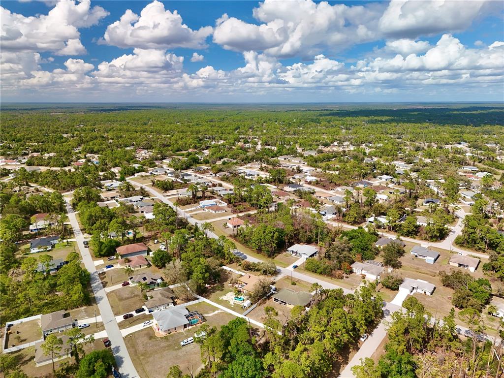 An aerial view shows a suburban neighborhood with houses surrounded by trees and vegetation — MERONI BOULEVARD, NORTH PORT, FL