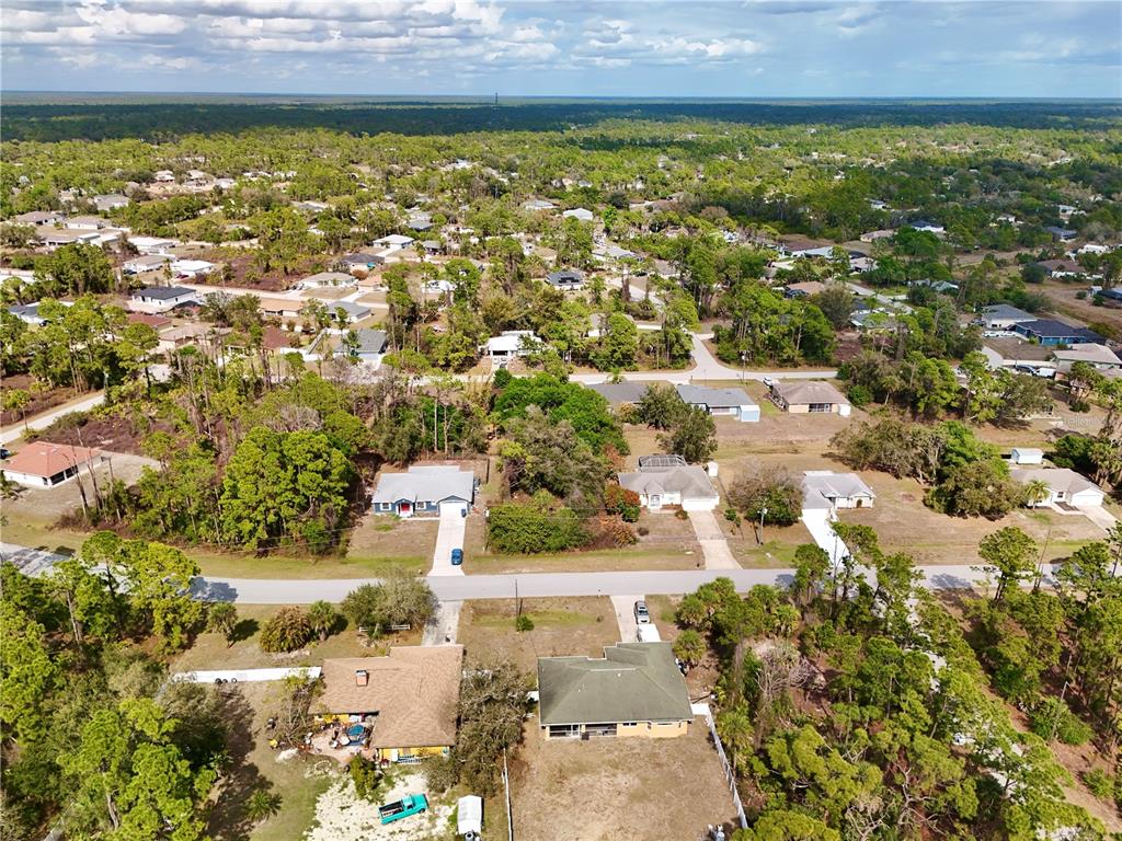 An aerial view shows several single-family homes surrounded by trees in a suburban neighborhood — MERONI BOULEVARD, NORTH PORT, FL