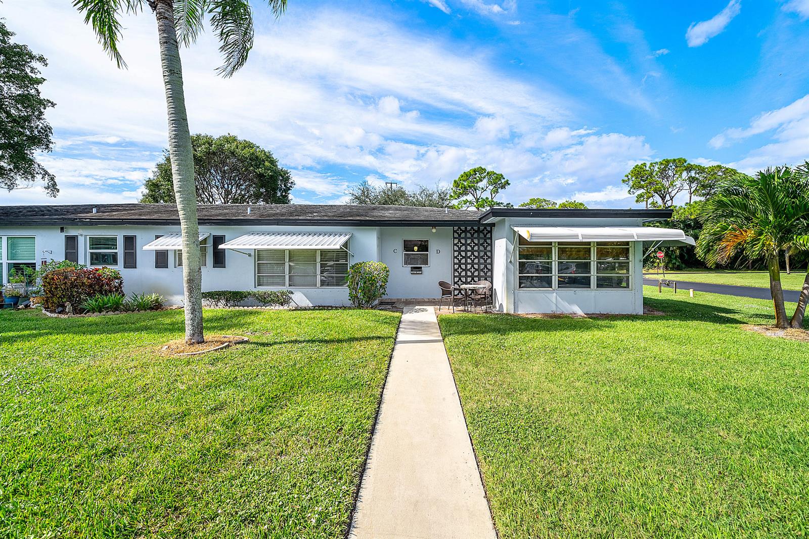 A white kitchen features stainless steel appliances, quartz countertops, and a decorative tile backsplash — 510 High Point Drive # D, Delray Beach FL 33445, DELRAY BEACH, FL