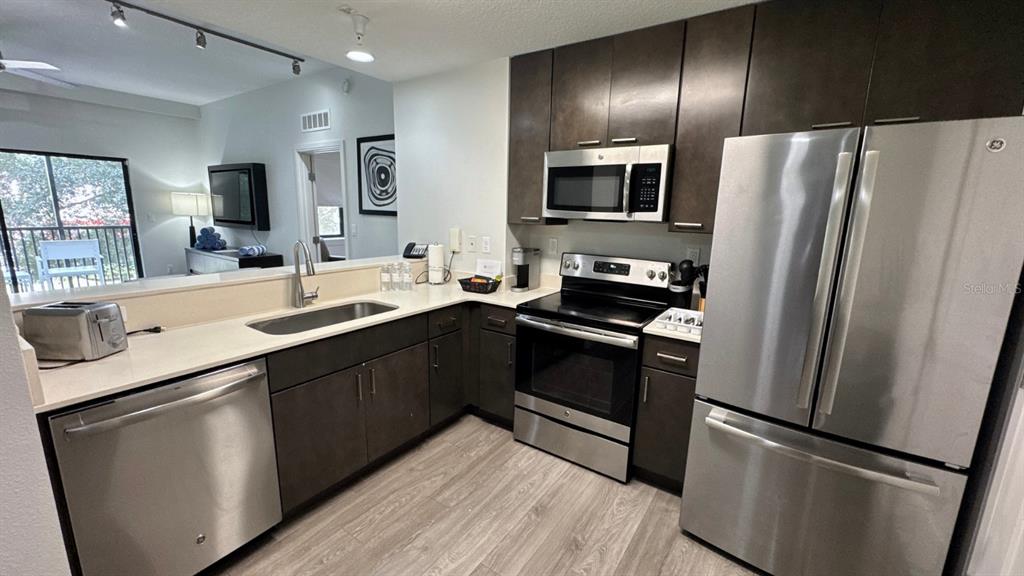 A kitchen features dark wood cabinets, stainless steel appliances, and light-colored countertops — 14501 GROVE RESORT AVENUE UNIT 3202, WINTER GARDEN, FL